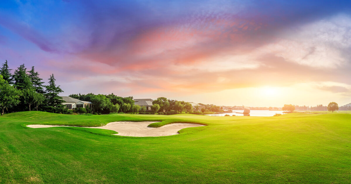 Golf course green and clubhouse at sunset