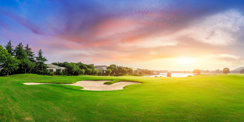 Golf course green and clubhouse at sunset