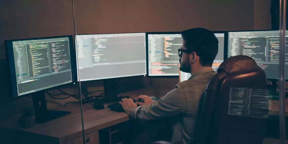 Developer working late at a four-monitor coding workstation