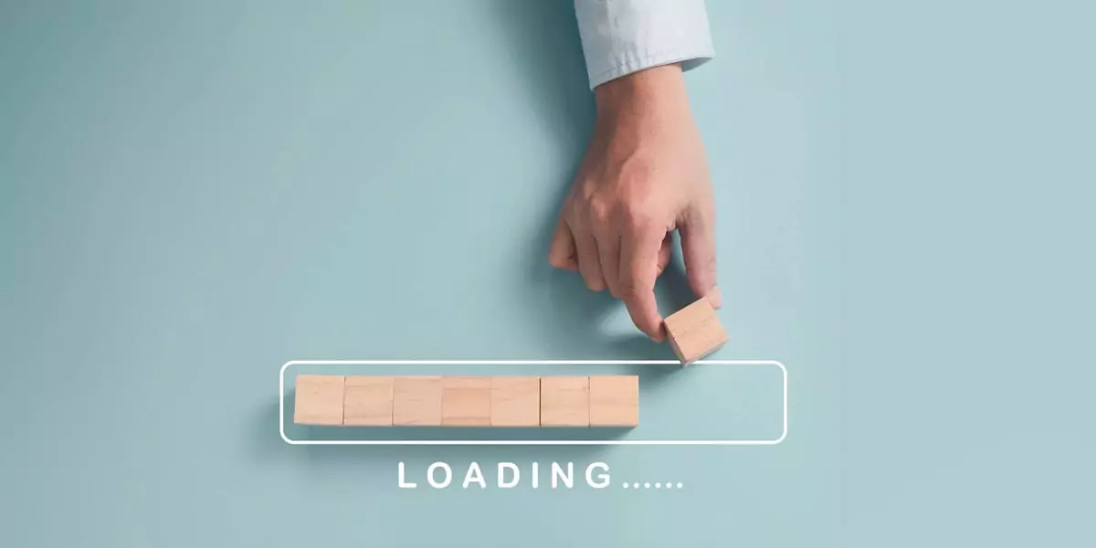 Hand placing a wooden block on a progress bar labeled Loading