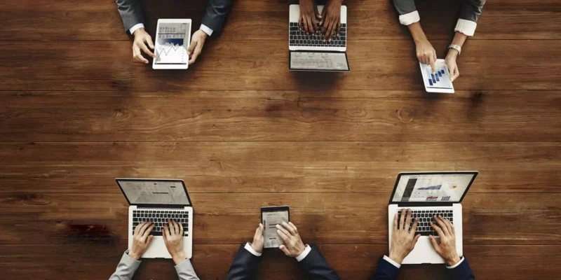 Overhead view of a business team collaborating with laptops and tablets showing charts