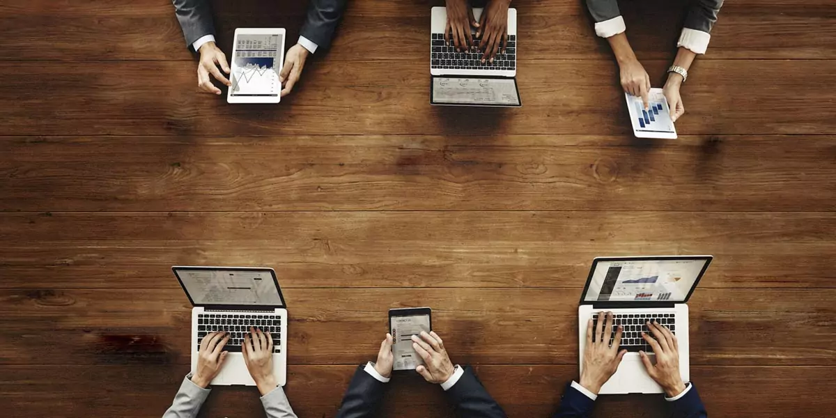 Overhead view of a business team collaborating with laptops and tablets showing charts