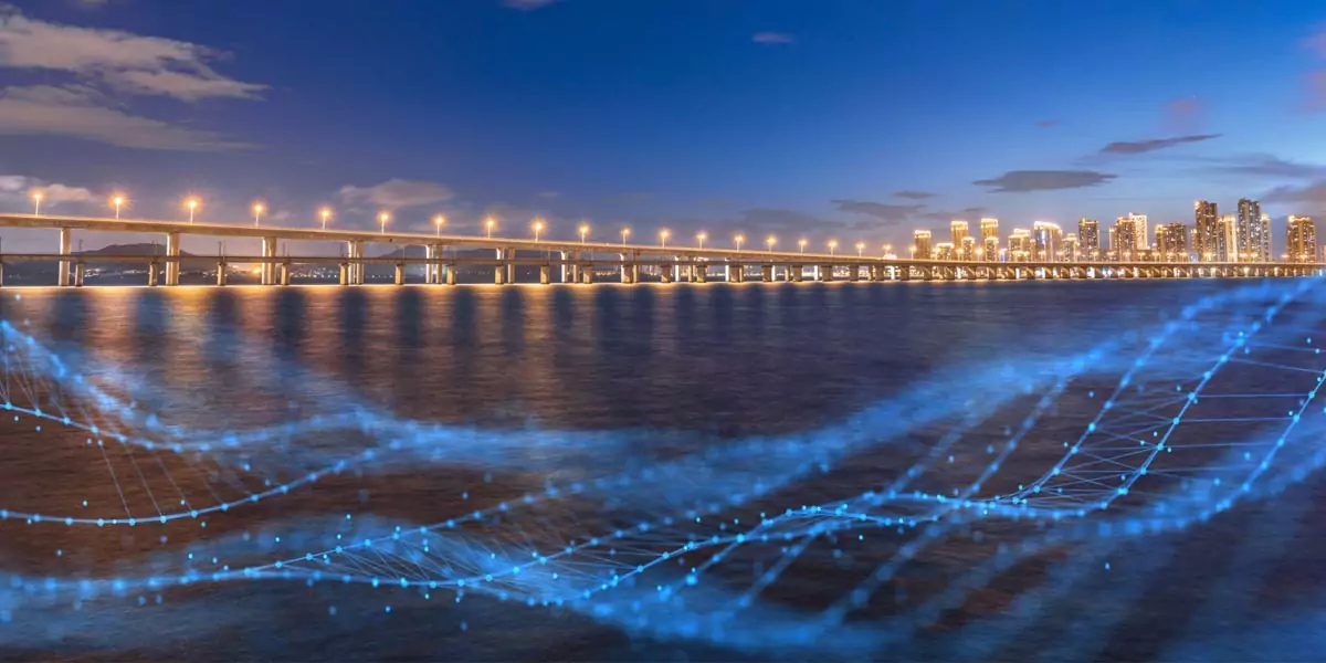 Bridge at night with a digital data stream flowing across the water