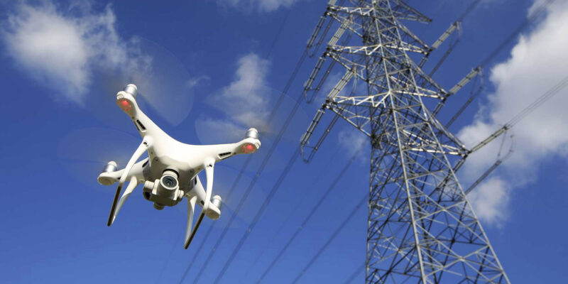 Drone flying near a high-voltage power transmission tower